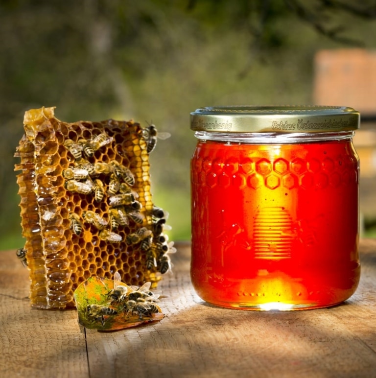 Honig mit Bienen vor den Stöcken